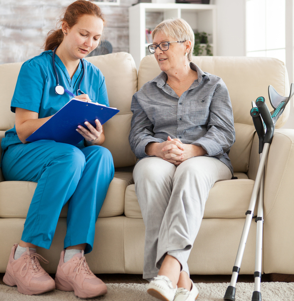 Female doctor with senior woman sitting on couch